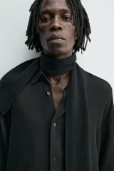 Camisa de corte relajado confeccionada en una mezcla de viscosa y algodón con textura. Presenta cuello solapa, cierre frontal de botones, manga larga con puños abotonados y aberturas laterales en el bajo.