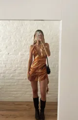 Vestido corto con estampado abstracto en tonos naranja, blanco y marrón. Diseño con escote halter y espalda descubierta.