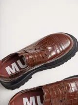 Mocasines color marrón con estampado de cocodrilo y plataforma negra con suela dentada.