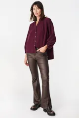 Camisa de pana color verde oliva, con cuello mao, cierre frontal de botones y mangas largas abullonadas con puños elásticos.