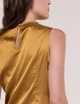 Blusa de satén color negro, de corte fluido, con escote asimétrico y un aro metálico decorativo en el hombro.