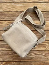 Bandolera color arena con correa de cuero y correa de tela intercambiables.
