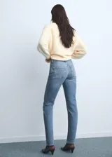 Jeans tipo mom-fit de tiro alto con diseño de cinco bolsillos, trabillas y cierre frontal con cremallera y botón.