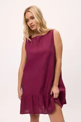 Vestido corto de color blanco, sin mangas, con escote bote y diseño suelto. Presenta un detalle de volado en el ruedo.