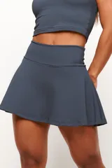 Short pollera de entrenamiento con cintura alta y diseño acampanado. Confeccionado en tejido de poliamida texturizado, cuenta con short interno y bolsillos laterales.