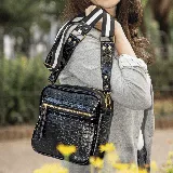 Bandolera negra de cuero vacuno con textura croco, correa larga ajustable y removible con diseño a rayas blancas y negras, bolsillo externo con cierre y forro interior de tela con bolsillo interno con cierre.