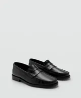 Zapato tipo mocasín de cuero vacuno color negro, con diseño de punta redonda, costuras visibles y detalle de antifaz en el empeine.