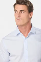 Camisa celeste de vestir, entallada, de manga larga, con cuello clásico y sin bolsillo.