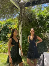 Vestido corto negro con estampado de plumas doradas, escote en V, breteles finos cruzados en la espalda, cut-outs laterales y volado en el ruedo.