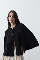 Saco tipo capa de punto color negro, con silueta fluida, corte amplio y cierre frontal con dos botones dorados.