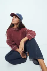 Buzo con capucha de calce relajado, confeccionado en tela con efecto lavado desgastado. Presenta costuras a la vista en color contrastante y un bolsillo frontal tipo canguro.