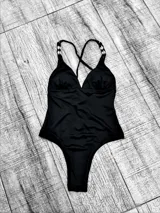 Malla entera negra con escote en V, breteles finos con detalle de caracoles y espalda cruzada.