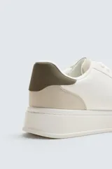 Zapatillas deportivas blancas con detalle de color gris en el talón y suela con volumen.