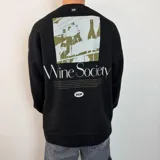 Buzo negro de corte oversize con estampado gráfico en la espalda que incluye una ilustración de botellas de vino, el texto 'Wine Society' y una descripción detallada, junto con el logo 'VCP'.
