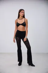 Pantalón de encaje negro, de corte ajustado en la parte superior y acampanado en la parte inferior.
