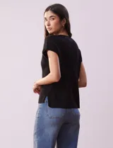 Buzo de tejido acanalado marca Tahari, con cuello redondo a la base y mangas tipo dolman. Presenta un diseño de líneas verticales y diagonales en el tejido.