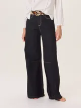 Pantalón ancho de algodón color verde oliva, con corte holgado desde la cadera hasta el tobillo. Presenta pinzas debajo de la rodilla, bordado de monograma en el bolsillo delantero y pespuntes a contratono.