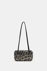 Bolso de hombro formato caja con estampado animal print cubierto de apliques brillantes. Posee doble asa de hombro, bolsillo interior y cierre imantado.