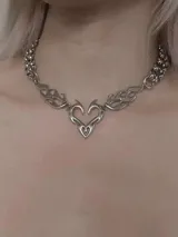 Collar plateado con cadena de eslabones y dije central con forma de corazón con detalles de llamas.