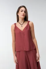Musculosa bordó de tejido satinado, con escote en V y breteles con detalle de nudos en los hombros.