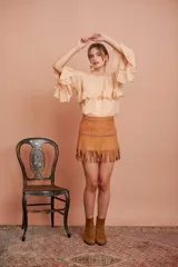 Minifalda color camel de gamuza con flecos en el ruedo y tachas plateadas en la cintura.