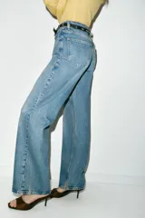 Jeans de tiro alto color azul claro, con cinco bolsillos y pernera recta que se estrecha hacia el tobillo. Incluye un cinturón negro con detalles metálicos. Cierre frontal con cremallera y botón.