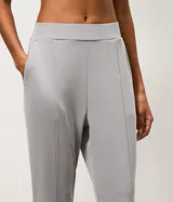 Pantalón deportivo femenino Get Over de corte flare, confeccionado en microfibra de color gris. Presenta cintura con pretina fija, diseño acampanado desde la rodilla y costuras decorativas frontales.
