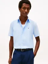 Camisa de manga corta Tommy Hilfiger en color celeste, confeccionada en tejido de popelina con tecnología flex. Presenta cuello clásico, cierre frontal con botones y el logo de la marca bordado en el pecho.