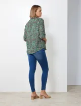 Blusa de gasa con estampado geométrico en tonos verdes, azules y morados. Presenta cuello con solapa, escote en V con botones y mangas largas que se pueden remangar y sujetar con presilla.