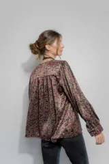 Camisa de seda con estampado floral en tonos bordó, marrón y negro. Presenta un corte amplio, escote en V con cierre frontal de botones, mangas largas abullonadas y detalles de frunce en hombros y espalda.