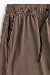 Short deportivo de tejido funcional con tecnología DryMove para absorción de sudor. Presenta corte estándar, cintura elástica con cordón de ajuste, bolsillos laterales y un bolsillo con cierre oculto. Incluye aberturas laterales en el bajo.
