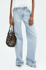 Jean wide leg de tiro alto en denim de algodón celeste claro, con diseño de cinco bolsillos, cierre de cremallera y botón metálico.