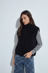 Chaleco de corderito negro con textura suave, cuello alto y cierre frontal completo. Cuenta con bolsillos laterales amplios y un diseño de calce relajado.