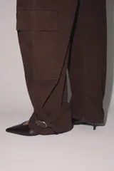 Pantalón cargo de tiro medio confeccionado en algodón, con diseño de pierna tipo barril. Presenta bolsillos laterales y bolsillos de plastrón con solapa en las piernas, además de un bajo ajustable con trabillas y hebilla metálica.