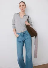 Pantalón de mezclilla de tiro medio con diseño acampanado estilo flare, trabillas para cinturón y clásico diseño de cinco bolsillos con cierre frontal de botón y cremallera.