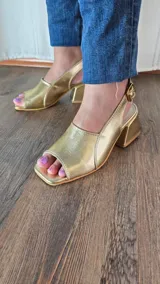 Sandalias de cuero color bronce, con taco cuadrado y tira ajustable con hebilla en el talón.