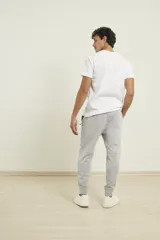 Pantalón de jogging color verde militar, corte slim, con puños elastizados en los tobillos y cordón ajustable en la cintura. Presenta un bolsillo lateral con cierre.