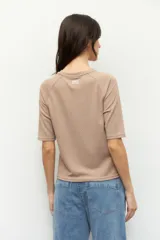 Remera negra de cuello redondo y manga tres cuartos, confeccionada en tela con textura sutil. Presenta fruncidos laterales que aportan caída y movimiento a la prenda.