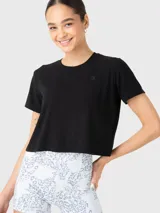 Remera de corte cropped, color negro, con cuello redondo y mangas cortas. Presenta una textura acanalada y un pequeño logo bordado en el pecho.