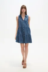 Vestido corto de denim sin mangas, con cuello camisero, cierre frontal con botones y diseño de falda con volados.
