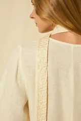 Minivestido blanco de lino con escote en V, mangas anchas acampanadas y bordados dorados en los puños, el dobladillo y el cinturón ajustable.