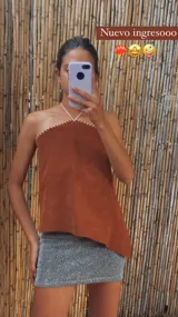 Top color ladrillo, sin mangas, con escote halter y detalle de costuras blancas en el borde superior.