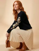 Suéter de punto negro con cuello redondo y bordados florales en hilo dorado en ambas mangas.