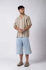 Camisa de manga corta tejida al crochet con diseño de rayas verticales negras sobre una base color crudo. Presenta cuello solapa y cierre frontal con botones.