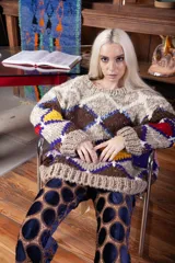 Sweater de lana tejido a mano con diseño de rombos multicolor en tonos tierra, rojo, amarillo y azul. Presenta un corte holgado, cuello redondo y puños acanalados.