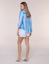 Blusa de gasa blanca con estampado floral multicolor, cuello con solapa, cierre frontal de botones y diseño anudado en la parte delantera.