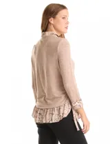 Buzo de tejido fino color beige con diseño de doble capa que simula una camisa debajo. Presenta cuello redondo, mangas largas con puños de gasa estampada en animal print, y ruedo con volado de la misma tela. Incluye detalles de frunces en los laterales.