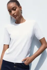 Jersey de punto fino con cuello redondo y manga corta, con terminaciones en rib en cuello, mangas y ruedo.