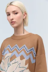 Sweater color camel de tejido de punto con cuello redondo y mangas largas. Presenta bordado de flor en el frente y la palabra 'Rebels' en la manga.