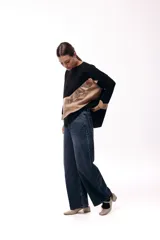 Sweater de punto con diseño de bloques de color en diagonal, combinando negro, beige y una franja central con textura metalizada. Presenta cuello redondo, mangas largas con puños en contraste y un corte holgado.